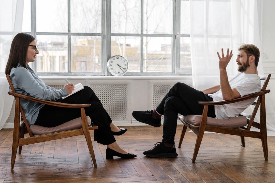 Två personer som sitter i stolar vända mot varandra och pratar.